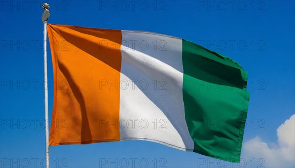 The flag of Ivory Coast flutters in the wind, isolated, against the blue sky