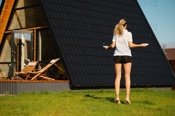 Mid adult a woman jumps with a smart rope on the lawn in front of tiny house