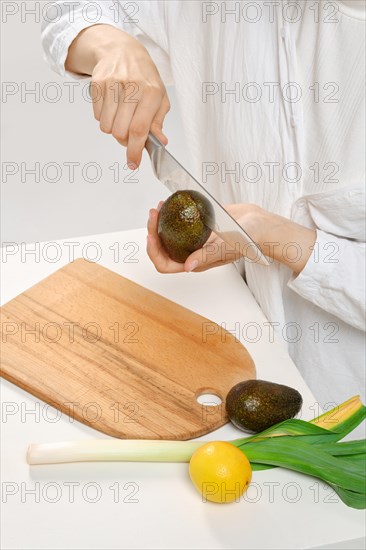 Unrecognizable woman cutting fresh avocado into halves. Concept of balanced eating