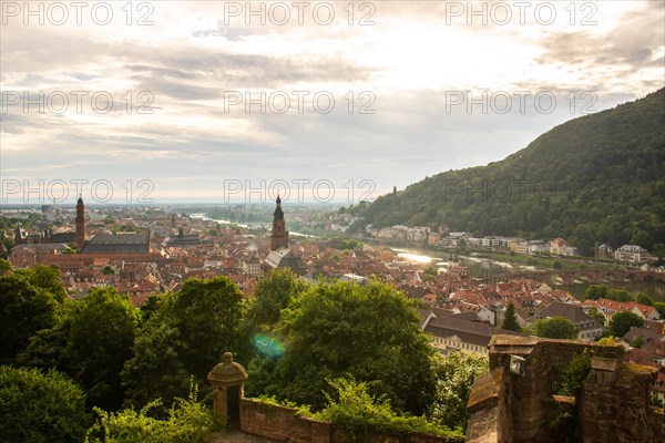 View over an old town with churches in the evening at sunset. This town lies in a river valley of the Neckar, surrounded by hills. Heidelberg, Baden-Wuerttemberg, Germany, Europe