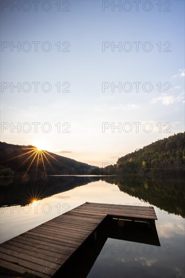 Lake at sunset. Beautiful landscape, taken from the shore of a reservoir. Situated in the middle of the forest and surrounded by nature, the reservoir offers a great atmosphere. Marbach Reservoir, Odenwald, Hesse, Germany, Europe