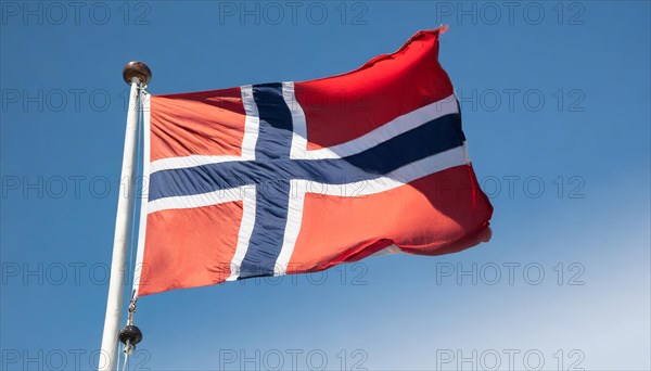 The flag of Norway flutters in the wind, isolated against a blue sky
