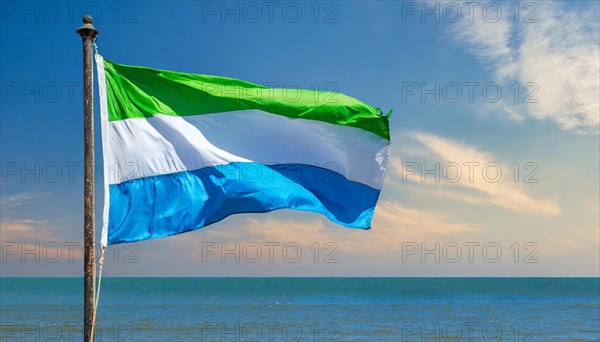 The flag of Sierra Leone, fluttering in the wind, isolated, against the blue sky