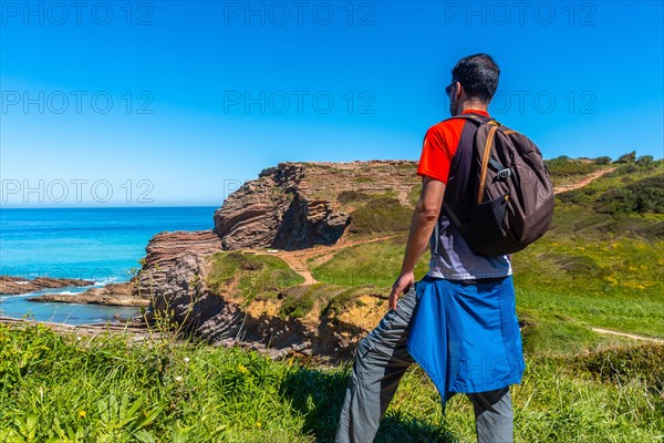 A hiker on a coastal path in the Algorri cove of the Zumaia flysch, Gipuzkoa. Basque Country