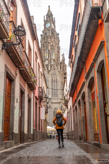A tourist woman walking along a beautiful street next to the Church of San Juan Bautista, Arucas Cathedral, Gran Canaria, Spain, Europe