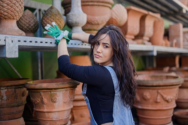 A woman arranging pots in a pottery shop, wearing protective gloves