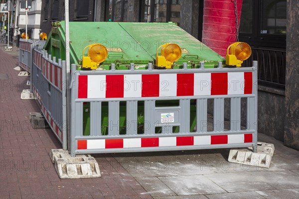 Construction site with barrier and waste container or skip for building rubble on a footpath, Germany, Europe