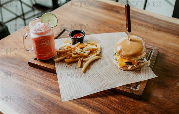 Top view of Hamburger with fries and strawberry mocktail served on a wooden table. Hamburger with strawberry cocktail served on a wooden table