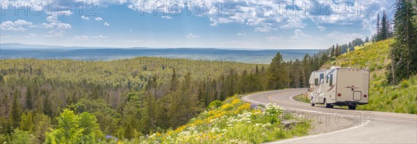 Banner of camper driving down road in the beautiful countryside among pine trees and flowers