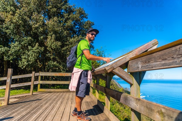 A tourist looking at an information panel at the Zumaia flysch in summer, Gipuzkoa. Basque Country