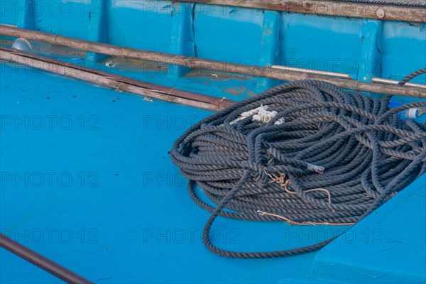 Black rope coiled up in bottom of blue fishing boat in South Korea