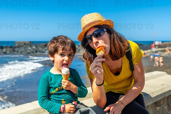 Mother with her little boy son enjoying summer vacation eating ice cream
