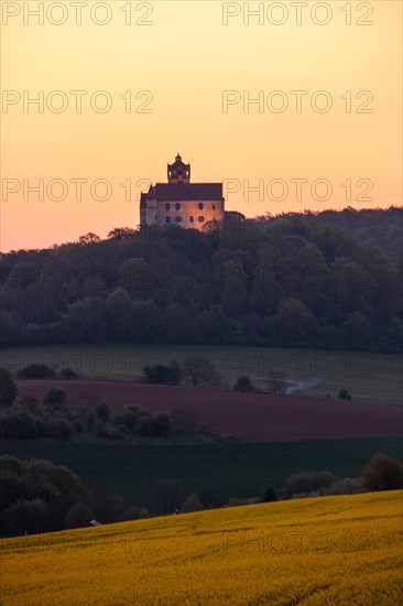 Landscape at sunrise. Beautiful morning landscape with fresh yellow rape fields in spring. Small castle in the yellow fields on a hill. Historic Ronneburg Castle in the middle of nature, Ronneburg, Hesse, Germany, Europe