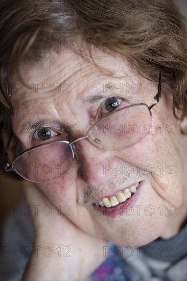 Portrait of a smiling senior woman with glasses in her living room, close-up, Cologne, North Rhine-Westphalia, Germany, Europe