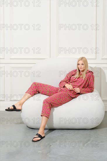 Beautiful blonde woman in a cozy home suit half laying on couch