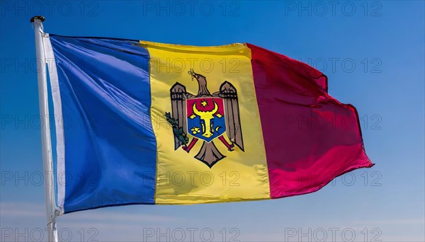 The flag of Moldova, Republic of Moldova, flutters in the wind, isolated against a blue sky