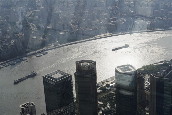 View from the 632 metre high Shanghai Tower, nicknamed The Twist, Shanghai, People's Republic of China, The sun shines through the skyscrapers onto a busy river, Shanghai, China, Asia
