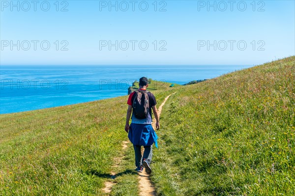 A hiker walking along a coastal path near the Zumaia flysch, Gipuzkoa. Basque Country