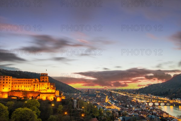 View over an old town with castle or palace rune in the evening at sunset. This town lies in a river valley of the Neckar, surrounded by hills. Heidelberg, Baden-Wuerttemberg, Germany, Europe