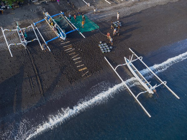 Fishermen unload their catch from their outrigger boat in the morning. Amed, Karangasem, Bali, Indonesia, Asia