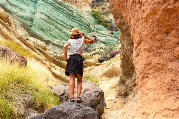 A tourist woman enjoying the natural monument at the Azulejos de Veneguera or Rainbow Rocks in Mogan, Gran Canaria