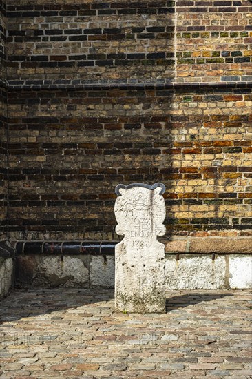 Boundary stone with the coat of arms and initials of St Mary's Church and the date 1672 renovat 1787, next to the main portal of St Mary's Church in the historic old town of Rostock, Mecklenburg-Western Pomerania, Germany, Europe