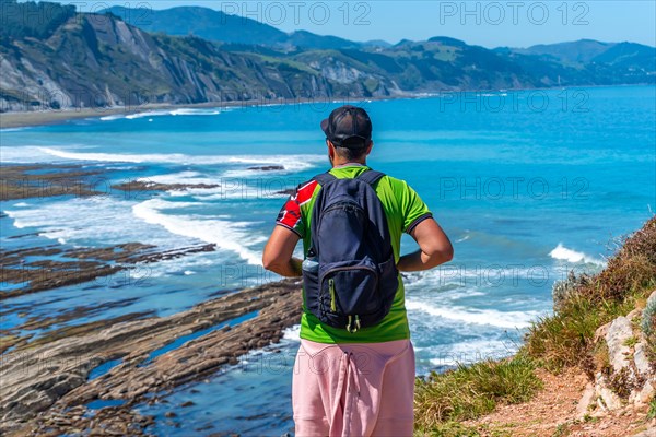 A man with his back turned in Algorri cove on the coast in the flysch of Zumaia, Gipuzkoa. Basque Country