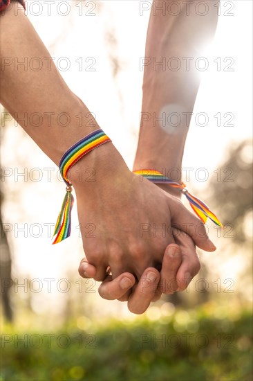 Vertical close-up of a gay men with rainbow bracelets holding hands