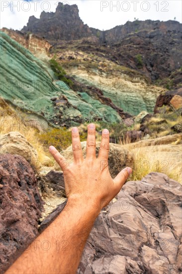 Hand of a man at the natural monument at the Azulejos de Veneguera or Rainbow Rocks in Mogan, Gran Canaria