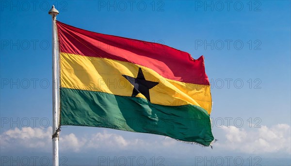 The flag of Ghana flutters in the wind, isolated against a blue sky