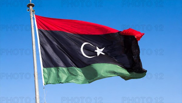 The flag of Libya, fluttering in the wind, isolated, against the blue sky