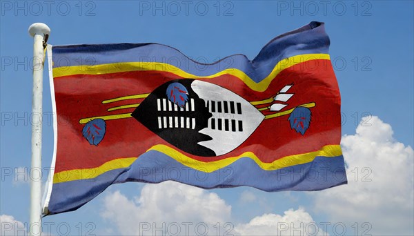 The flag of Swaziland, Kingdom of Eswatini, flutters in the wind, isolated, against the blue sky