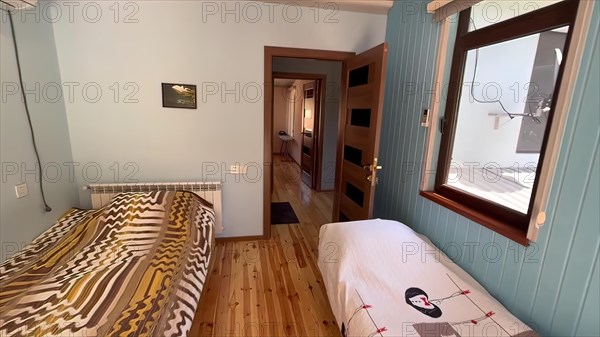 Interior of a hotel room with a double bed and wooden floor