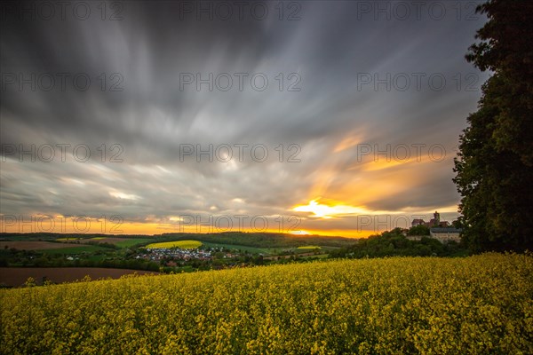 Landscape at sunrise. Beautiful morning landscape with fresh yellow rape fields in spring. Small castle in the yellow fields on a hill. Historic Ronneburg Castle in the middle of nature, Ronneburg, Hesse, Germany, Europe