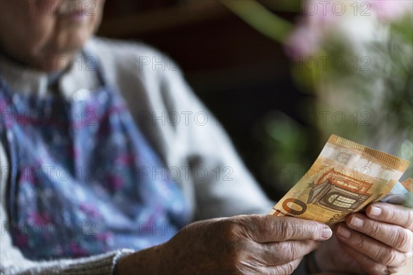 Senior citizen with wrinkled hands counts her money at home in her flat and holds banknotes in her hand, Cologne, North Rhine-Westphalia, Germany, Europe