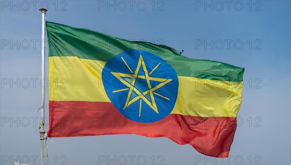 The flag of Ethiopia, fluttering in the wind, isolated against a blue sky