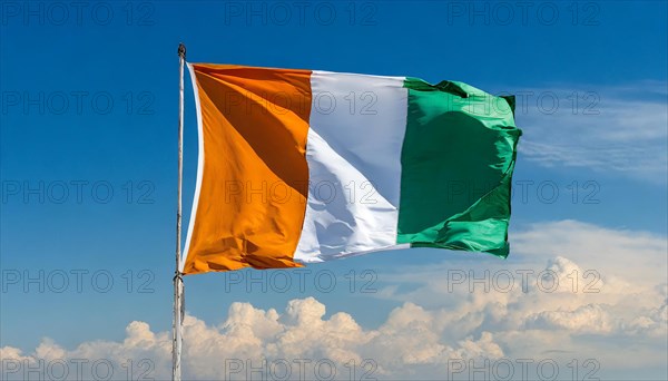 The flag of Ivory Coast flutters in the wind, isolated, against the blue sky