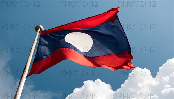 The flag of Laos flutters in the wind, isolated against a blue sky