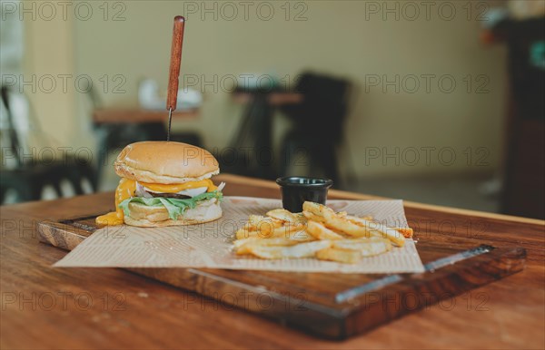 Cheeseburger with french fries served on wooden table with copy space. Delicious hamburger with french fries on a wooden table