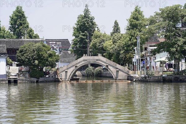Excursion to Zhujiajiao water village, Shanghai, China, Asia, wooden boat on canal with view of historical architecture, old stone bridge over a calm river with reflections in the water, Asia