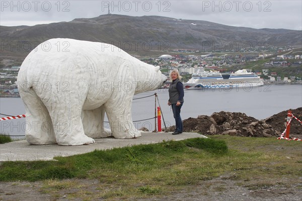 Polar bear sculpture in front of the town of Hammerfest with cruise ship Aida in the harbour, Northern Norway, Scandinavia