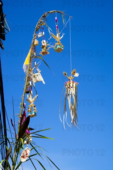 Ornate jewellery woven from palm leaves on bamboo poles, on a village street in Amed, Karangasem, north-east Bali, Indonesia, Asia