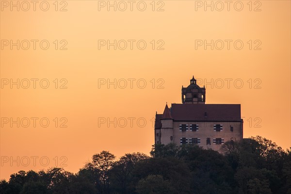 Landscape at sunrise. Beautiful morning landscape with fresh yellow rape fields in spring. Small castle in the yellow fields on a hill. Historic Ronneburg Castle in the middle of nature, Ronneburg, Hesse, Germany, Europe