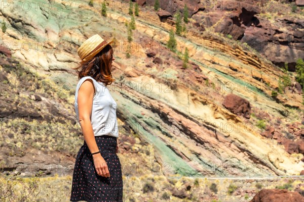 A tourist woman at the Natural Monument Azulejos de Veneguera or Rainbow Rocks in Mogan, Gran Canaria