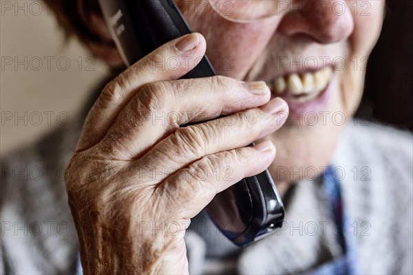 Mouth, hands and telephone receiver of a senior citizen making a phone call, close-up, Cologne, North Rhine-Westphalia, Germany, Europe