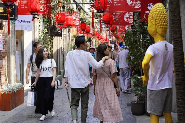 Stroll through the restored Tianzifang neighbourhood, A lively pedestrian zone with red decorations and a statue, Shanghai, China, Asia