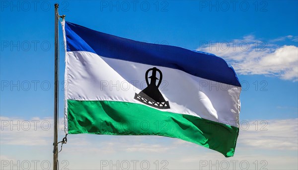 The flag of Lesotho, fluttering in the wind, isolated, against the blue sky