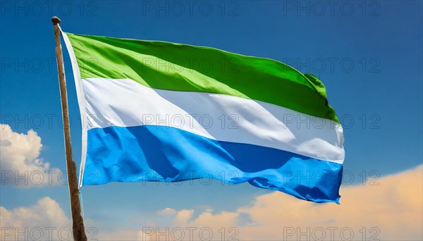 The flag of Sierra Leone, fluttering in the wind, isolated, against the blue sky