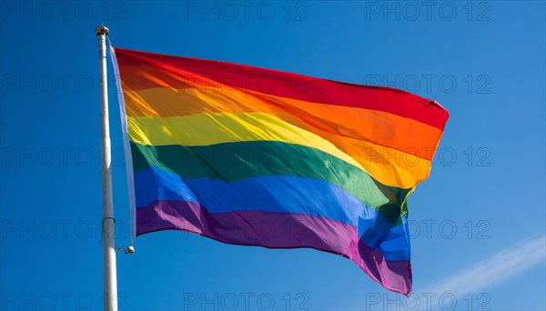 The rainbow flag flutters in the wind, isolated, against the blue sky. In many cultures around the world, such a flag expresses the mood for peace, new beginnings and change. It is also a symbol of tolerance and acceptance of the diversity of lifestyles, of hope and longing