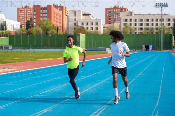 Full length photo of two smiling young african runners training together in an outdoors athletics track
